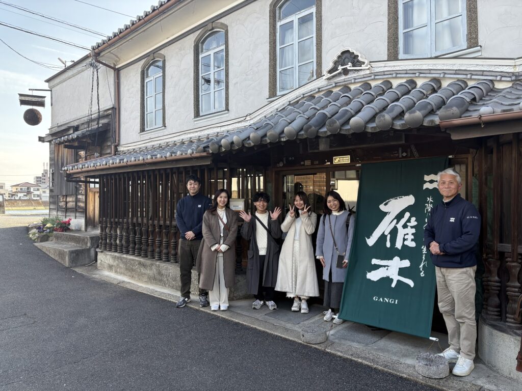 雁木の暖簾とともに記念撮影をする酒小町メンバー